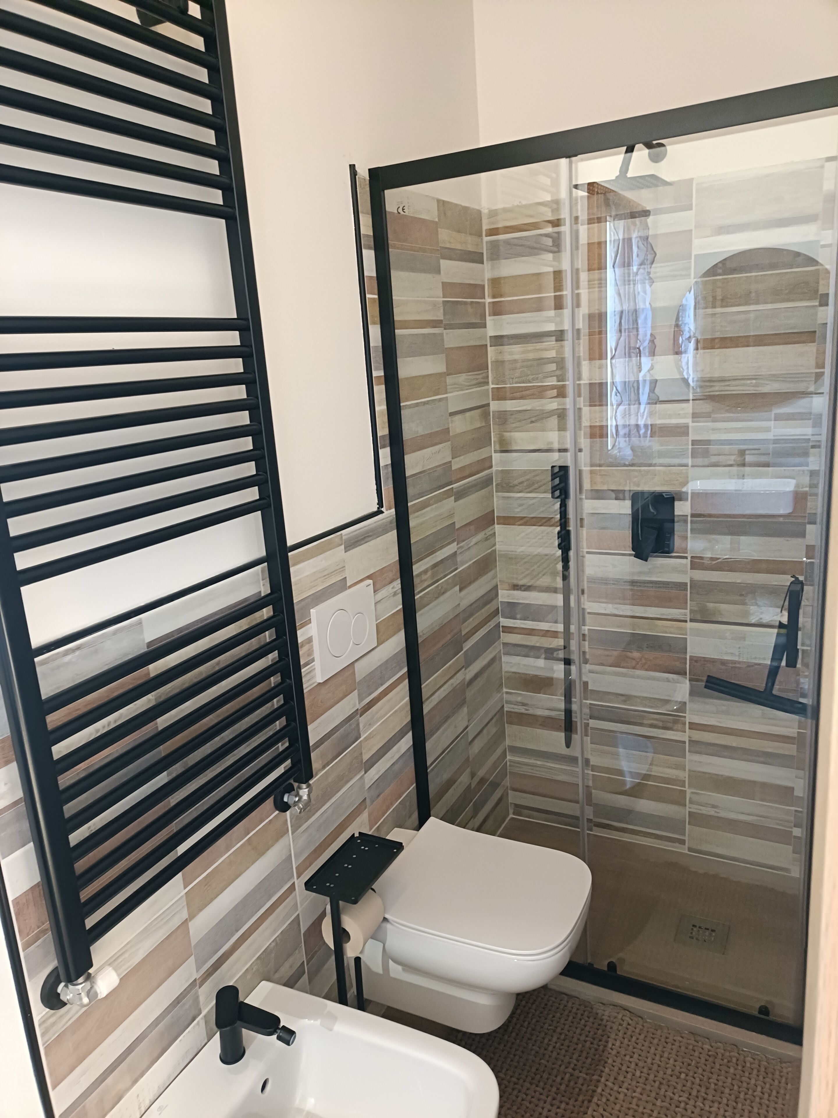 A modern bathroom with a glass shower enclosure, a toilet, and a sink with a black faucet.