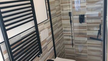 Un baño moderno con cabina de ducha de vidrio, inodoro y lavabo.