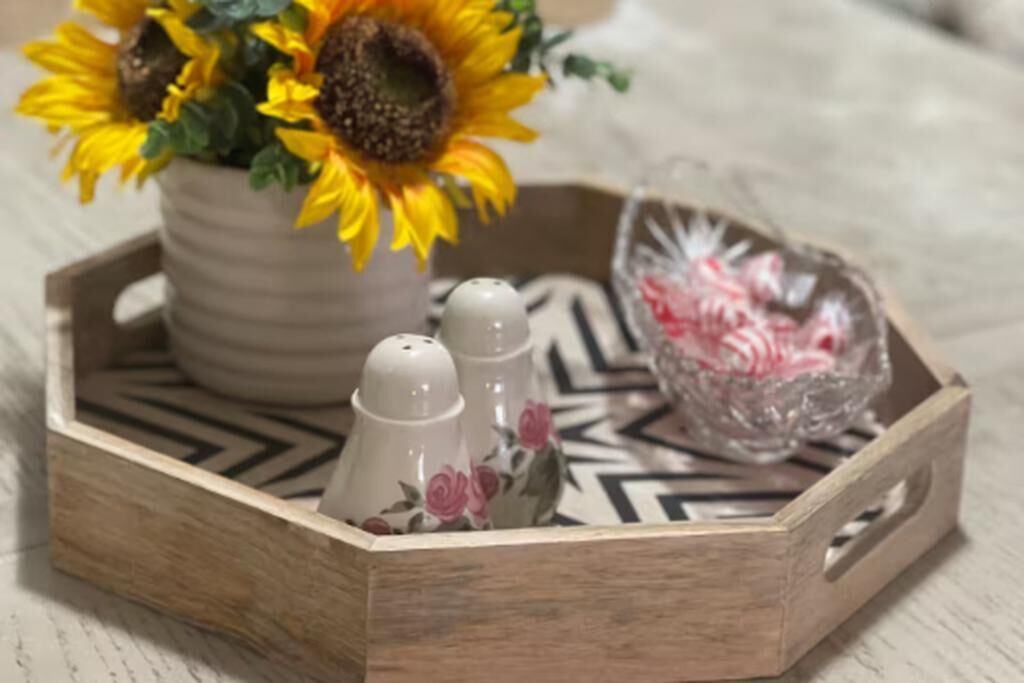 Un plateau en bois avec une fleur de tournesol, des salières et des poivrières, et un bol en verre décoratif.