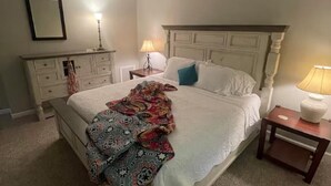A bedroom with a bed, bedside tables, a dresser, and a lamp.