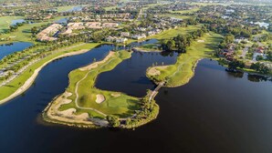 Vista aérea de un campo de golf con obstáculos acuáticos, búnkeres de arena y un puente.