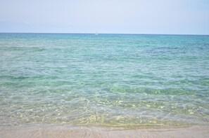 A beach with clear water, a distant buoy, and a clear sky. - Apartment 'La Rosa Dei Venti' with Shared Pool and Air Conditioning (Viddalba)