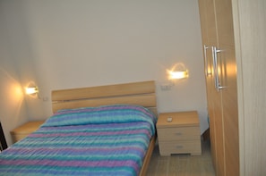 Een slaapkamer met een bed, nachtkastjes, een kledingkast en wandlampen.