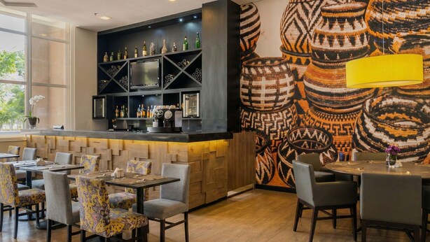 A restaurant with a bar area, wooden flooring, and patterned wall art. - Studio Bed Queen-size (Guarulhos)