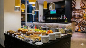 Een buffetgedeelte met diverse gerechten en een bar op de achtergrond.