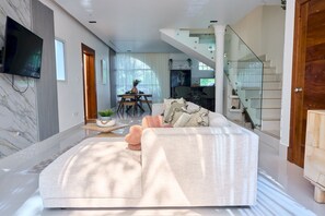 Una sala moderna con un sofá grande, un comedor y una escalera.