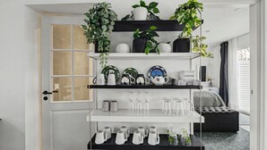A white shelving unit with various items including potted plants, decorative plates, and glassware. - Hambo Hideaway - Private guest house with fenced patio near Malmö & Lund (Staffanstorp)