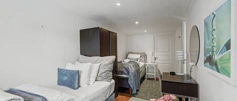 Una habitación compacta con una cama, un escritorio y una silla. Hay un espejo en la pared, una puerta y un radiador.