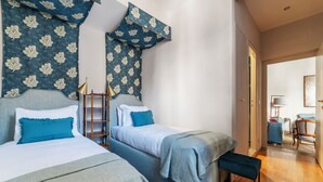 Ett hotellrum med två sängar, en bänk, en trästege och utsikt över korridoren.