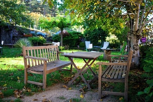 Um conjunto de banco e mesa de madeira num jardim com relva e árvores.