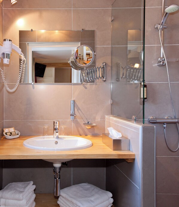 A modern bathroom with a sink, mirror, towel rack, and shower.