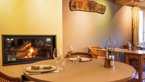 Un comedor con chimenea, una mesa redonda para dos personas y una obra de arte colgada en la pared.