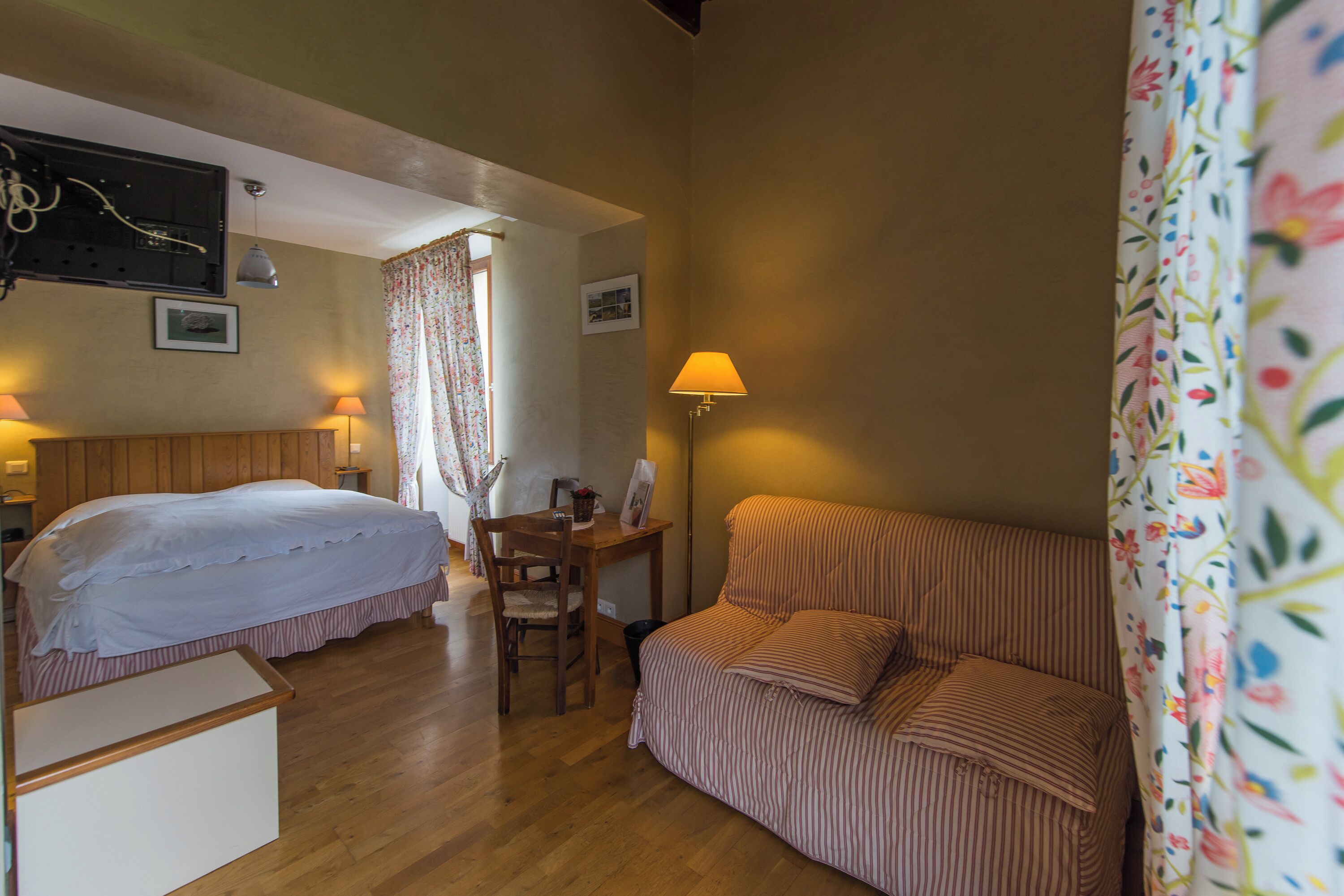 Una habitación con cama, escritorio, silla, sofá y lámpara.