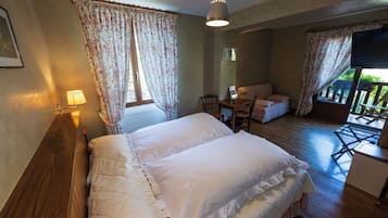 Une chambre à coucher comprenant un lit, un bureau et une chaise, une fenêtre avec des rideaux et un téléviseur fixé au mur.