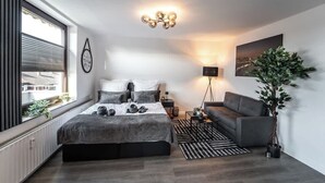 A modern bedroom with a large bed, a sofa, a floor lamp, and a potted plant. - Stern Blick: Maisonette, Balkon, zentral in Bremen (Bremen)