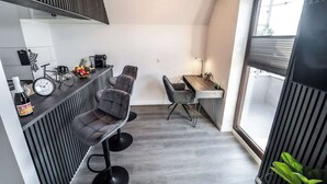 A compact kitchen with modern appliances, a dining area with bar stools, and a large window providing natural light. - Stern Blick: Maisonette, Balkon, zentral in Bremen (Bremen)