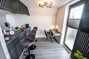 A compact kitchen with modern appliances, a dining area with bar stools, and a large window providing natural light. - Stern Blick: Maisonette, Balkon, zentral in Bremen (Bremen)