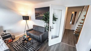 A modern living room with a grey sofa, a floor lamp, a coffee table, and a black and white striped rug. - Stern Blick: Maisonette, Balkon, zentral in Bremen (Bremen)