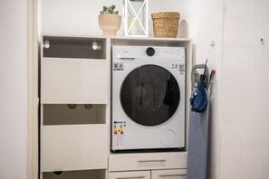 Una safareig compacte amb una rentadora de càrrega frontal, un escuraprius i un petit armari amb calaixos.