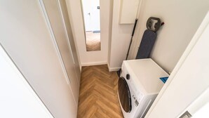 A laundry room with a washing machine, a mop, and a door leading to another room. - Stadionperle | Direkt im Viertel | Gruppenliebling (Bremen)