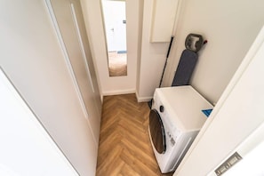 Une buanderie équipée d’un lave-linge, d’une serpillière et d’une porte donnant sur une autre pièce.