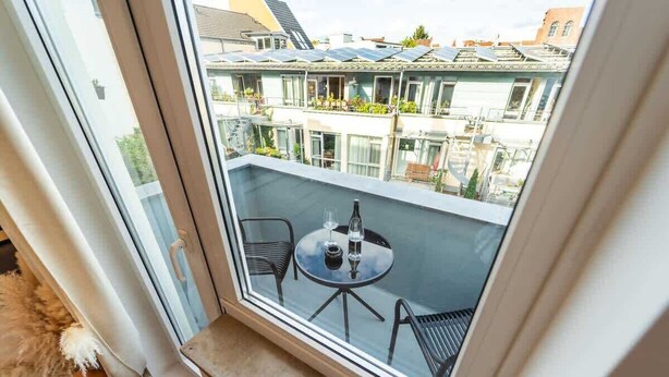 A balcony with a glass table and chairs, a bottle, and a small potted plant. - Stadionperle | Direkt im Viertel | Gruppenliebling (Bremen)