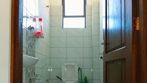 Et lille, rent badeværelse med toilet, håndvask og brusebad.