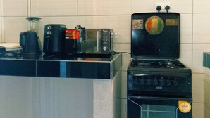 Et køkken med kaffemaskine, mikrobølgeovn og komfur.