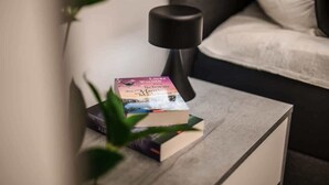 Een nachtkastje met boeken en een lamp in een hotelkamer.