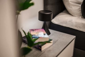 Un comodino con libri e una lampada in una camera d'albergo.