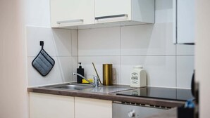 Een keuken met witte kasten, een roestvrijstalen spoelbak, een koffiezetapparaat en een afwassysteem.