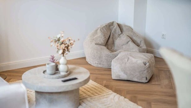 Un salon moderne avec une table basse ronde, un pouf beige et un tapis blanc.