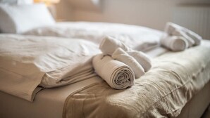 Un lit bien fait, avec une serviette enroulée et un oreiller.