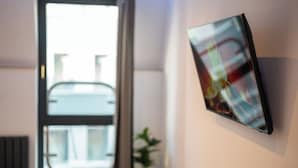 Una habitación moderna con un ventanal grande, un televisor montado en la pared y una planta en maceta.