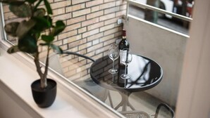 A balcony with a potted plant, a glass table with a bottle and two glasses, and a brick wall in the background. - Exklusive 1-Zimmer Stadtwohnung in Bremen (Bremen)