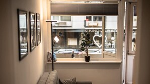 A cozy corner with a cushioned bench, a potted plant, and a window with blinds. - Exklusive 1-Zimmer Stadtwohnung in Bremen (Bremen)