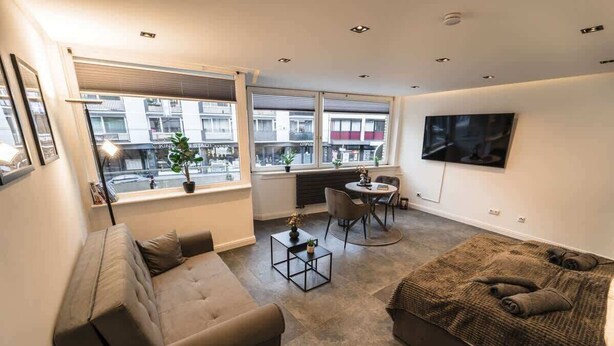 A modern living room with a sofa, a coffee table, and a TV mounted on the wall. - Exklusive 1-Zimmer Stadtwohnung in Bremen (Bremen)