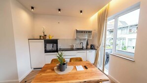 Une cuisine de taille réduite avec des meubles blancs, une table à manger en bois et des chaises jaunes.