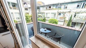 Un balcon avec une porte-fenêtre, une petite table ronde et deux chaises.