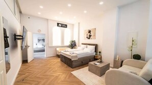 Una camera da letto moderna con un letto, un divano, un tavolino da caffè e una televisione.