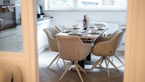 Una cucina moderna con zona pranzo, con un tavolo apparecchiato per quattro persone, una bottiglia di vino e una macchina da caffè.