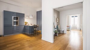 Een moderne keuken met grijze kastjes, een ingebouwde oven en een eethoek met een tafel en stoelen.