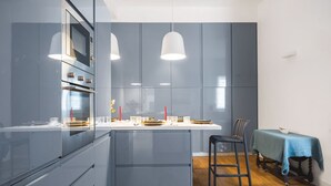 Een moderne keuken met een centraal eiland, ingebouwde apparatuur en hanglampen.