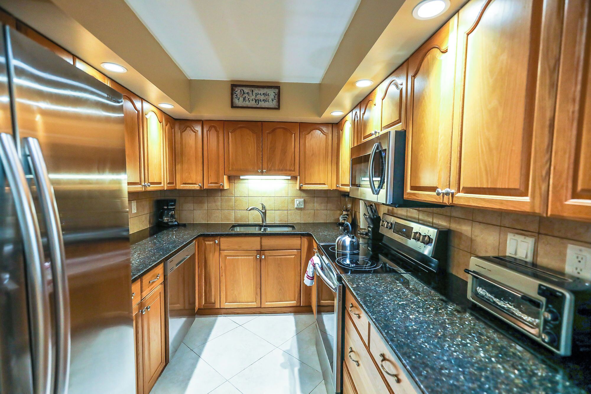 A modern kitchen with wooden cabinets, stainless steel appliances, and a built-in oven.