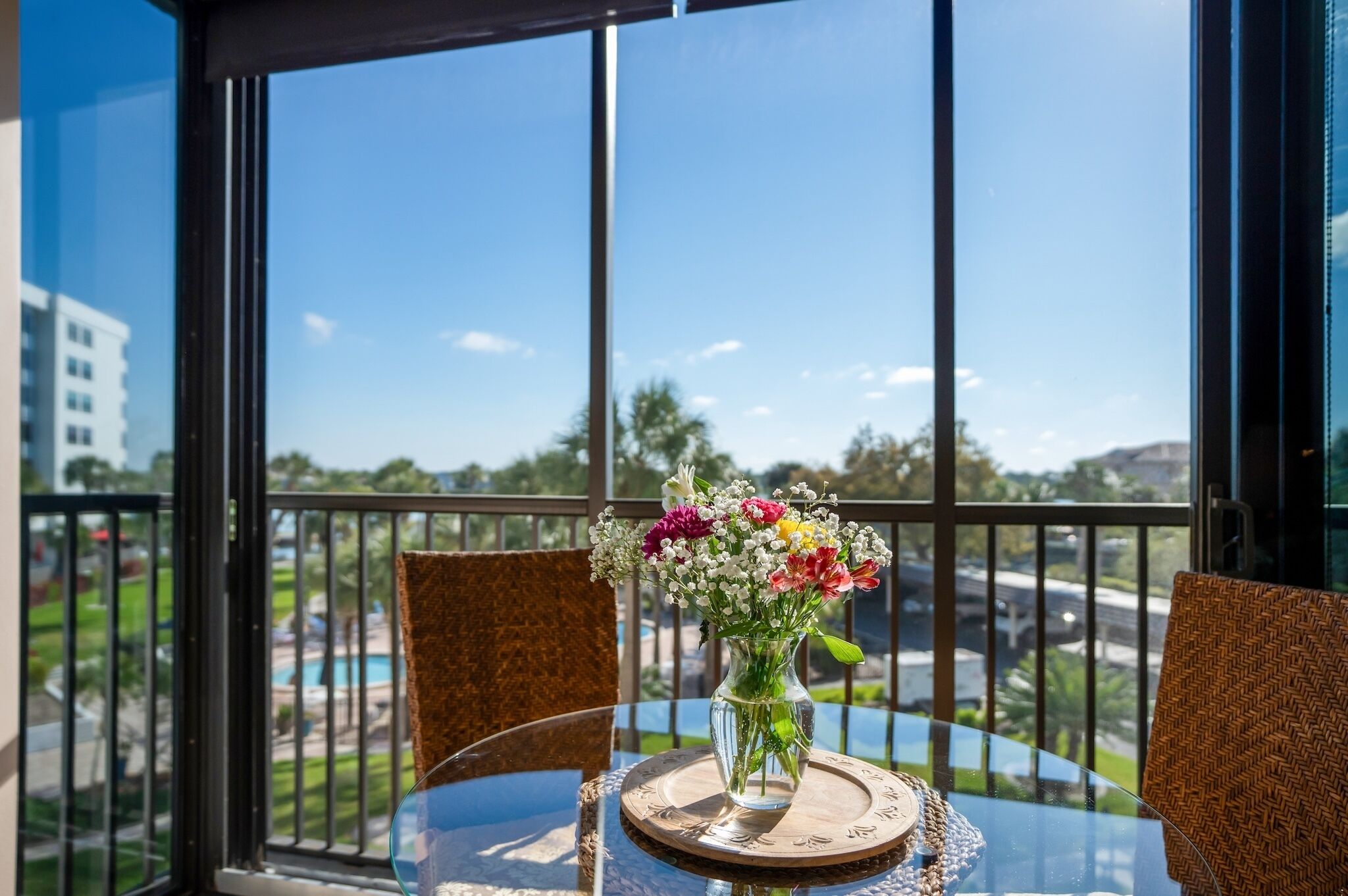 A balcony with a table, chairs, and a vase of flowers.