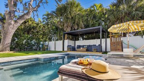 A backyard with a swimming pool, a covered seating area, and a slide. - Luxury Family Getaway w/ Pool, Putting and Backyard Fun (Anna Maria)