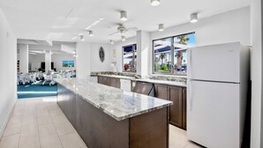 Une cuisine moderne avec un plan de travail en marbre, des meubles de rangement en bois foncé et un réfrigérateur blanc.