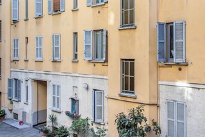 A multi-story building with multiple windows and shutters, some open and some closed. - Modern and Elegant Apt (Milan)