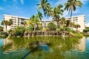 Un hotel con piscina, palmeras y una cascada.
