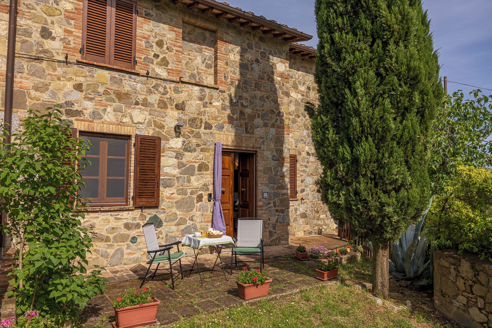A stone building with a patio, outdoor seating, and potted plants.